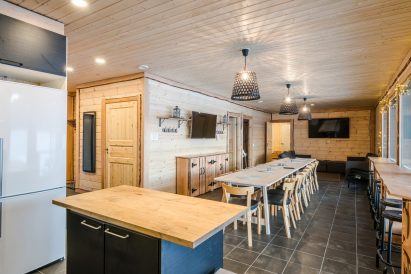 Aulangon Rantahuvilan pääsali. Etualalla tupakeittiö, keskellä ruokapöytä ja maisemabaaritiski.