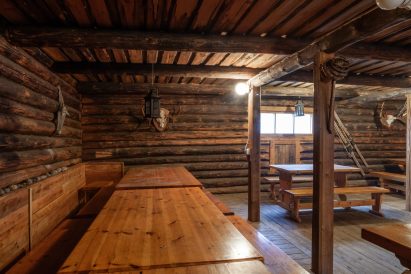 Evon Ruuhijärven juhla-aitan sisustusta hallitsevat jyhkevät tukeista halkaisemalla valmistetut penkki- ja pöytäryhmät