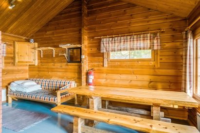 Evon Syväjärven saunan pukuhuoneen jykevän pöytäryhmän ääressä kelpaa vilvoitella löylyjen välissä. Vuodesohva sopii 1-2 hengen lisävuoteeksi läpi vuoden.