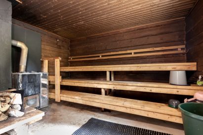 Evon Erähuvilan pihalla sijaitsevan perinteisen puulämmitteisen saunan tunnelmallinen löylyhuone ja pesutila.