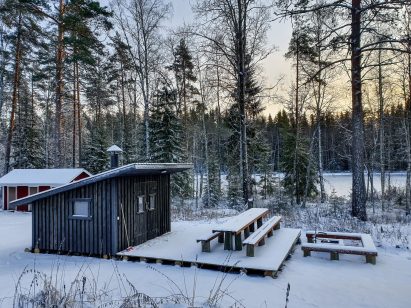 Evon Kaksikon alapihalla on erähenkisesti sisustettu grillikota, jonka edessä on erillinen ulkotulipaikka.