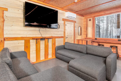 Lopen Luksuksen pääsalin sohvaryhmä ja toinen salin taulutelevisioista. Taustalla ikkunaseinän maisemabaaritiski.