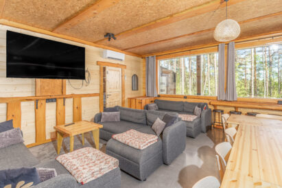 Lopen Luksuksen pääsalin sohvaryhmä ja toinen salin taulutelevisioista. Taustalla ikkunaseinän maisemabaaritiski.