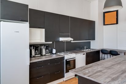 Räyskälän Suuren Huvilan pääsalin päädyssä oleva avokeittiö on kattavasti varustettu ja tarjoaa hyvän tilan myös omatoimiseen kokkailuun hyvässä seurassa.